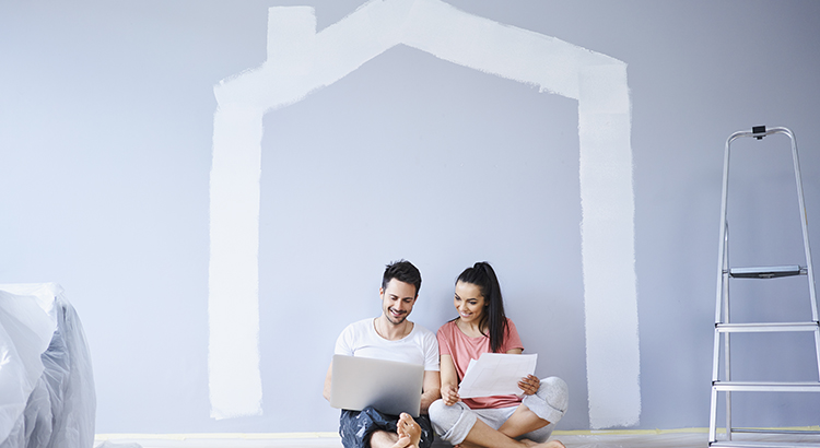 Couple sitting in new apartment using laptop