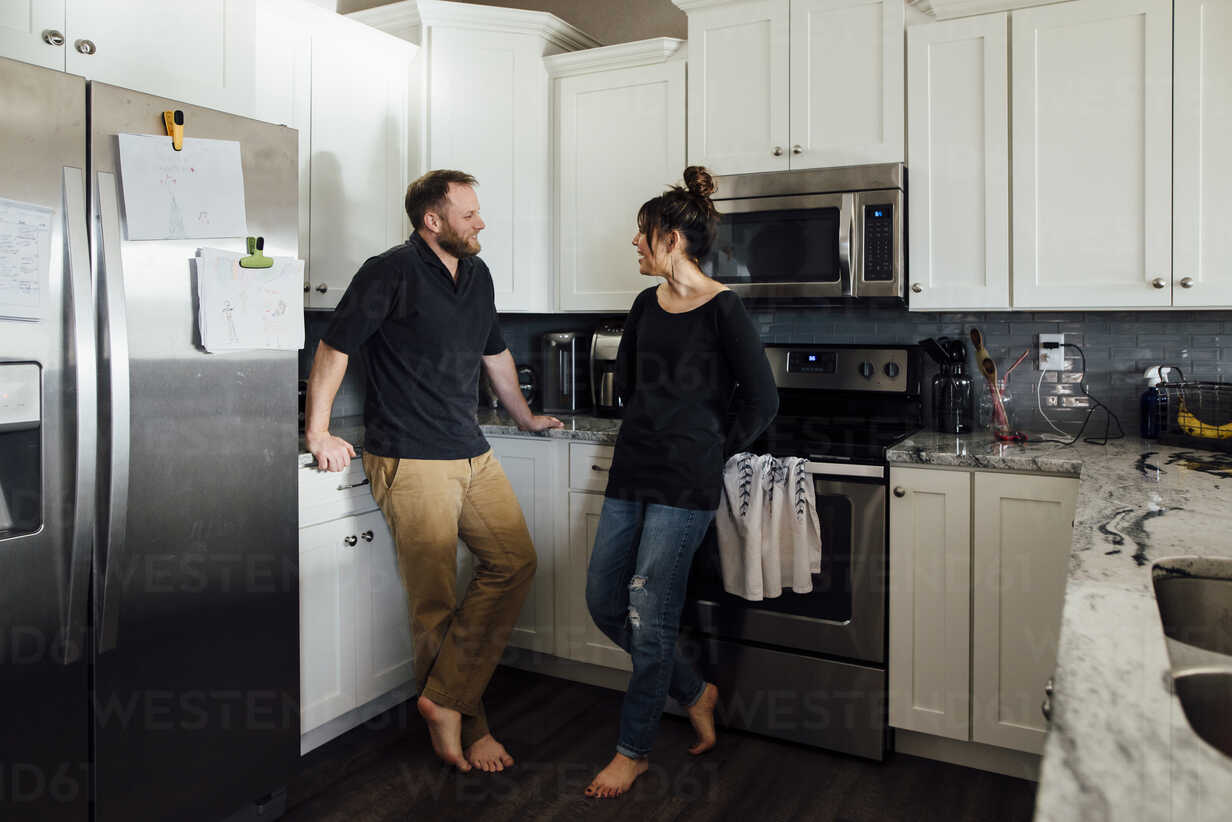 Couple talking while standing in kitchen at home