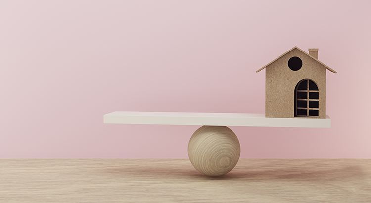 House a balance scale in equal position on wooden table and pink background. financial management, depicts short term borrowing for a residence.