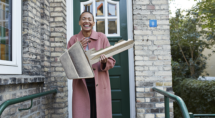 Cheerful woman holding large key outside new house