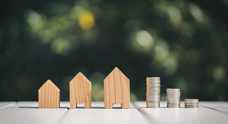 Close-Up Of Wooden Model Homes And Stacked Coins On Table